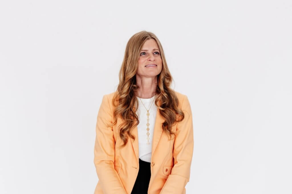Allie Pepper seated in a peach blazer, looking to the side